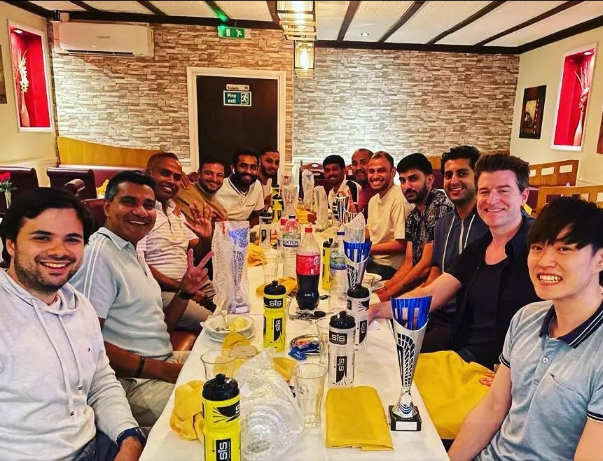 Supersonic players celebrating three team promotions at the end-of-season dinner, trophies on the table